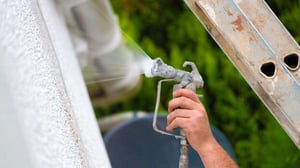Exterior wall coatings being spray-applied to an external building wall to improve its finish and provide a protective surface.