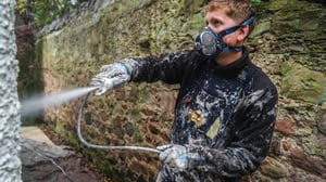 Exterior wall coatings being applied to a stone wall using specialist spray equipment in Scotland.