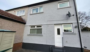 Wall Refurbishment Process showing a house with a freshly refurbished exterior wall finish in light grey, complemented by charcoal detailing.