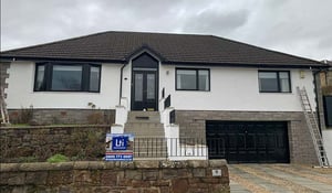 Exterior wall coating on a Scottish home with a white rendered finish, dark roof tiles and stone-effect lower walls.