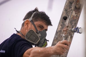 Exterior wall coatings being spray-applied by a professional wearing protective equipment to create a durable finish on an external wall.
